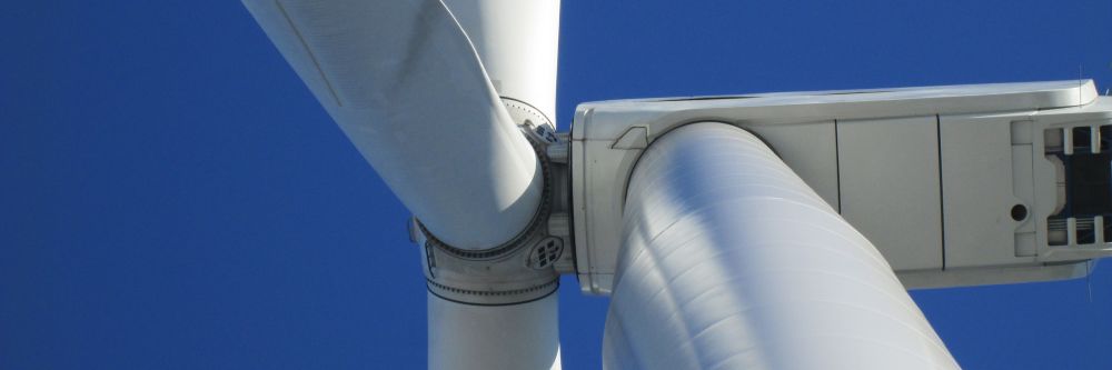 The nacelle and blades of a Nordex N90 Gamma wind turbine on a blue sky day
