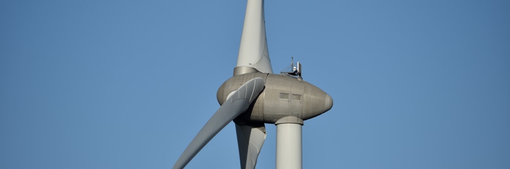 A large wind turbine against a blue sky during a life extension inspection